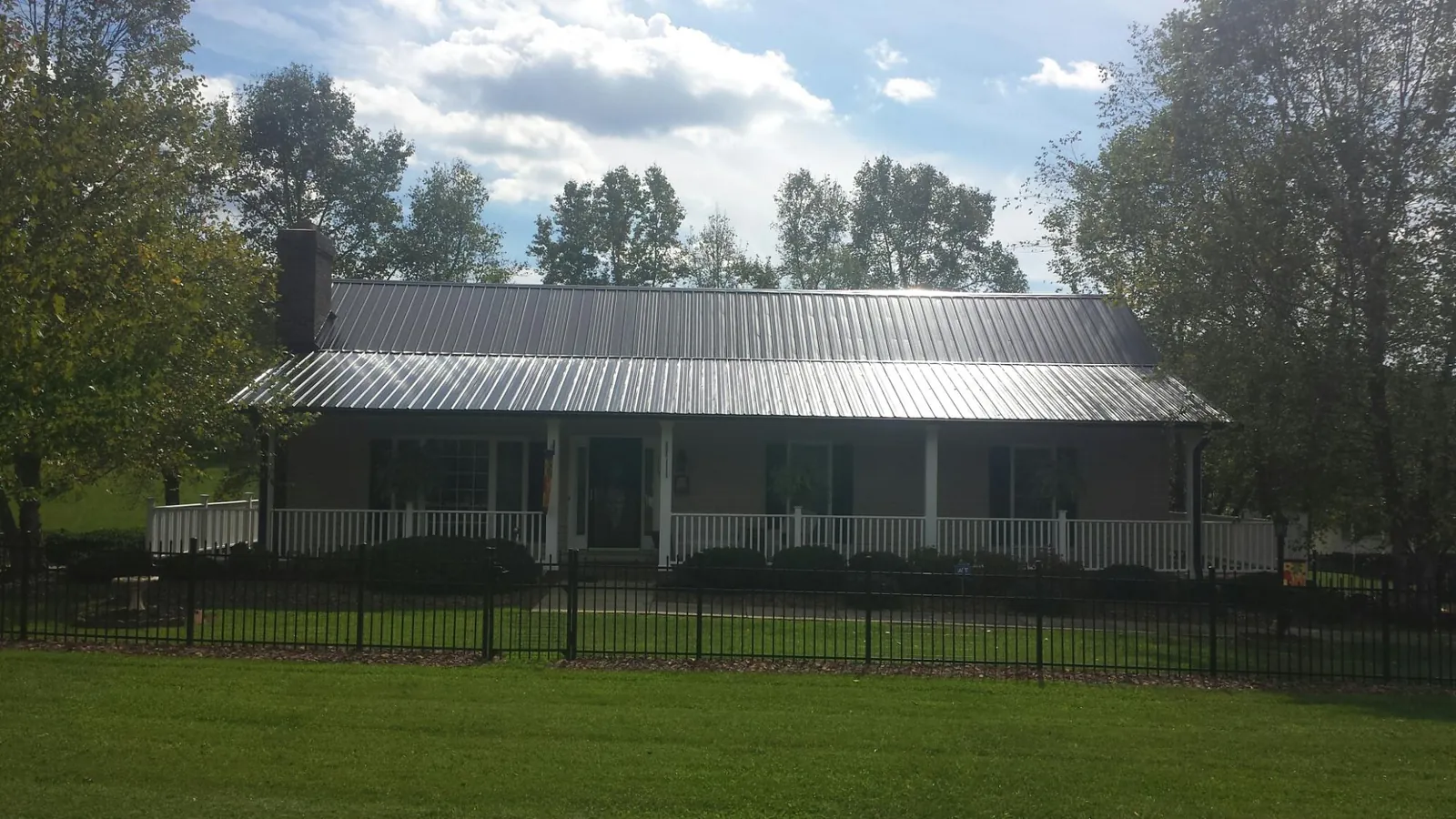 Gray metal roof on a brick ranch with a full width front porch — Gutter Guard Installation work by our crew in Westover